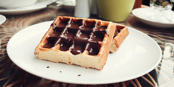 Vienna Waffles with chocolate topping. Aged photo. Delicious dessert. White plate with Chocolate covered Wafers. Toned. Delicious dessert. Wide photo for wallpaper or site slider.