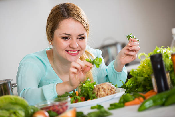 istock Young woman decorating salad with herbs in kitchen 609625110