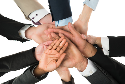 Directly below shot of business team stacking hands against white background