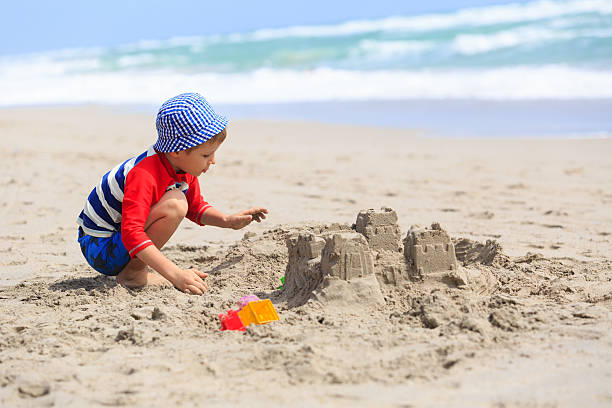 istock little boy play with sand on summer beach 609685970