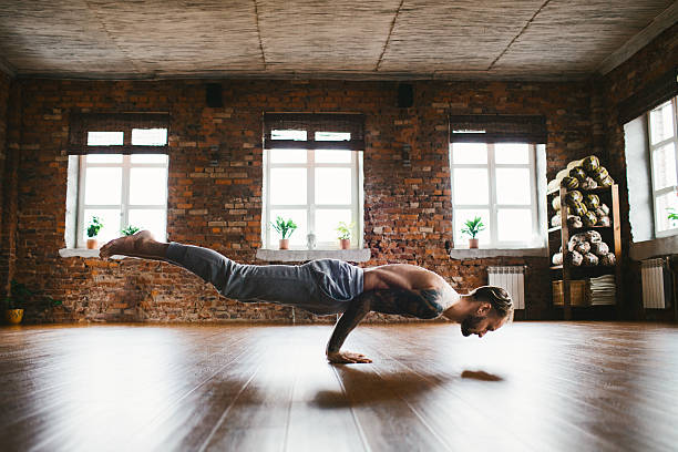 Man doing yoga in studio Young Caucasian man doing yoga in studio man yoga tattoo stock pictures, royalty-free photos & images