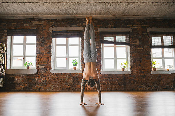 homme faisant du yoga en studio - équilibre sur les mains photos et images de collection