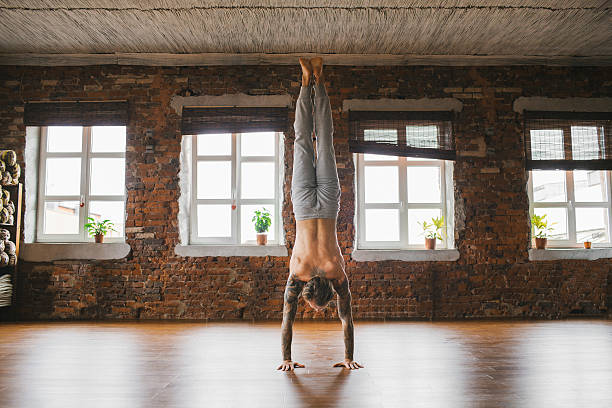 Man doing yoga in studio Young Caucasian man doing yoga in studio man yoga tattoo stock pictures, royalty-free photos & images