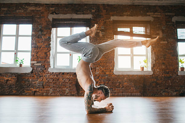 Man doing yoga in studio Young Caucasian man doing yoga in studio man yoga tattoo stock pictures, royalty-free photos & images