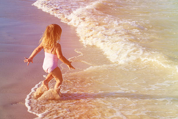 istock little girl run play with waves on the beach 609686716