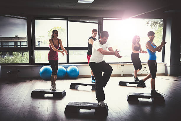 groupe de personnes de faire aérobic dans la salle de sport - in step photos et images de collection