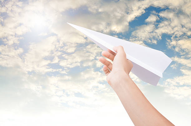 istock Hand holding paper plane toward cloudy blue sky. 609689592