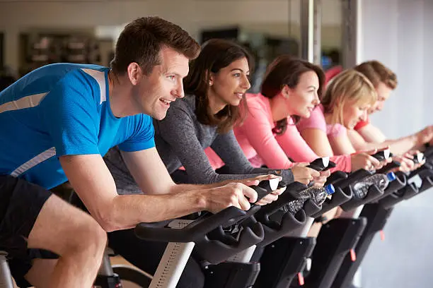 Side view of a exercising class on exercise bikes at a gym