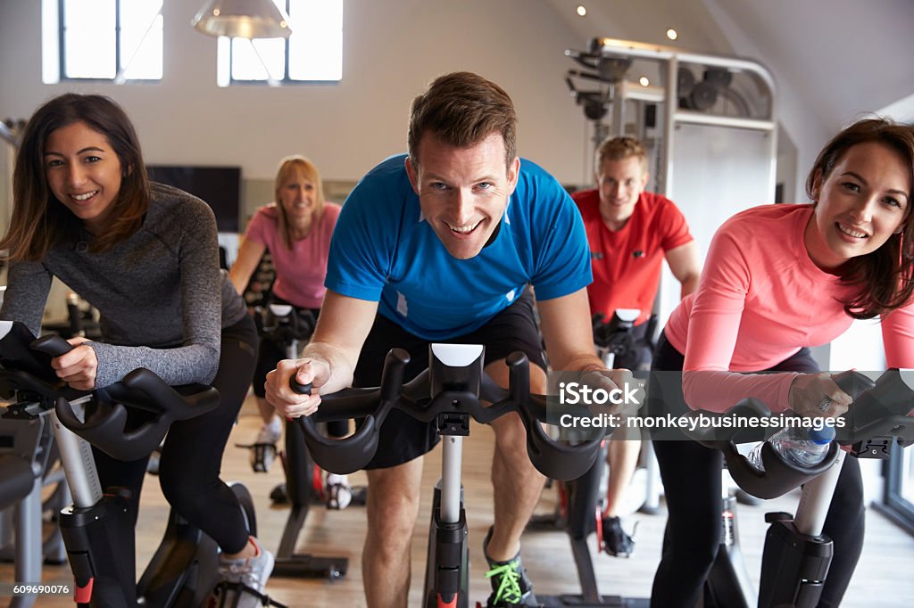 exercising class on exercise bikes at a gym looking exercising class on exercise bikes at a gym looking to camera Exercise Bike Stock Photo