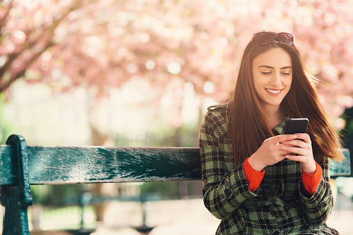 Woman texting outdoors in the spring.