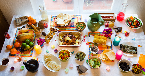 This is a table with some food from latin america, as fried plantain, arepas, hallaca, black beans, avocado, tortilla and some fruits.