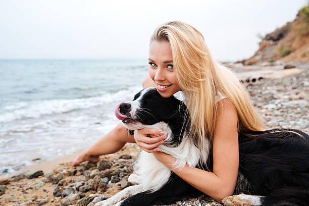 istock Smiling woman with her dog on the beach 609693476