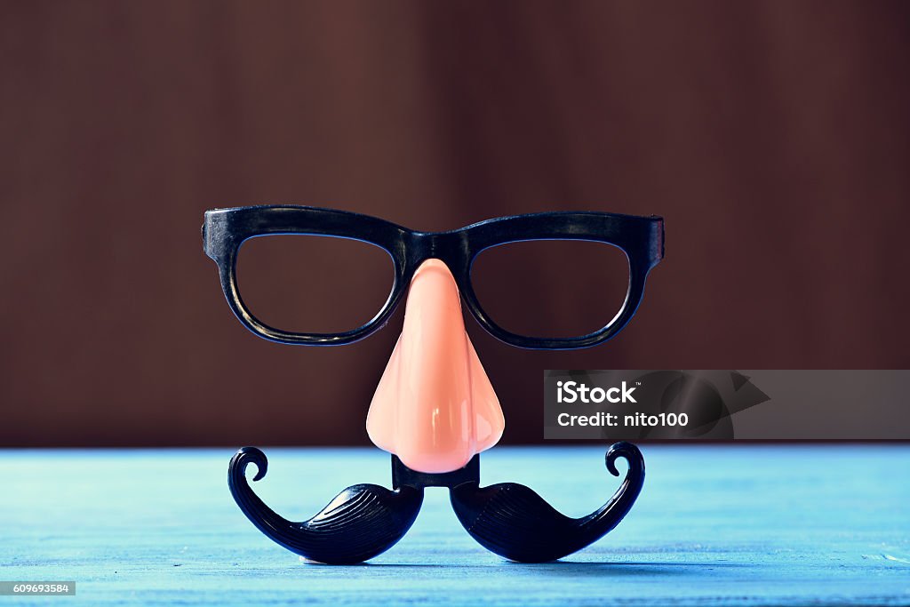 fake mustache, nose and eyeglasses on a blue surface closeup of a fake mustache, nose and eyeglasses on a rustic blue wooden surface Mask - Disguise Stock Photo