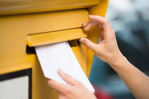 manos de mujer insertando carta en el buzón - sending mail fotografías e imágenes de stock