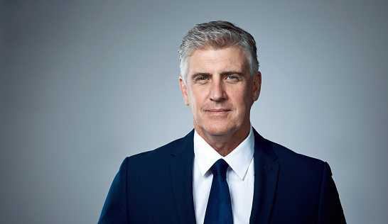 Studio portrait of a mature businessman posing against a grey background