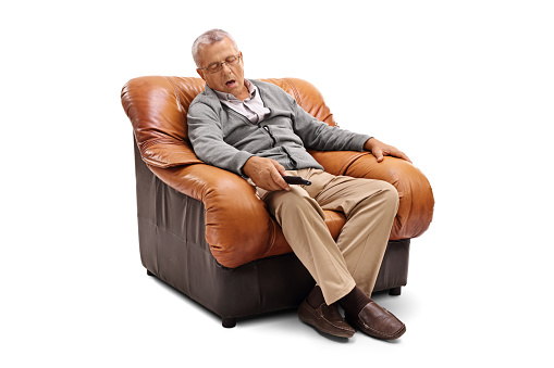 Tired senior sleeping on an armchair and holding a remote isolated on white background