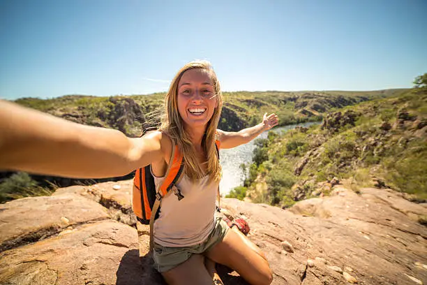 Cheerful young woman takes a selfie portrait with the Katherine Gorges on the background. Beautiful Summer day, the girl shows a personal perspective of her travels.