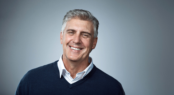Studio shot of a happy mature man posing against a grey background