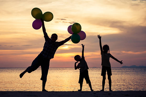 istock Father and children playing on the beach at the sunset. 609698720