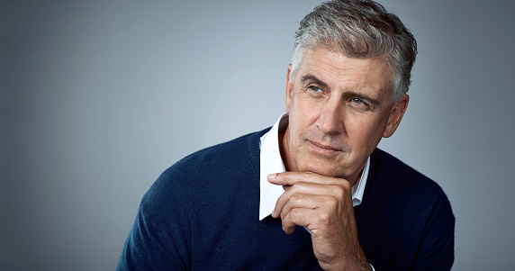 Studio shot of a thoughtful mature man posing against a grey background