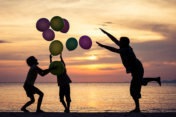 istock Father and children playing on the beach at the sunset. 609699448