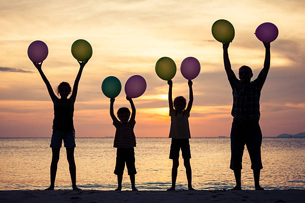 istock Father and children playing on the beach at the sunset. 609699890