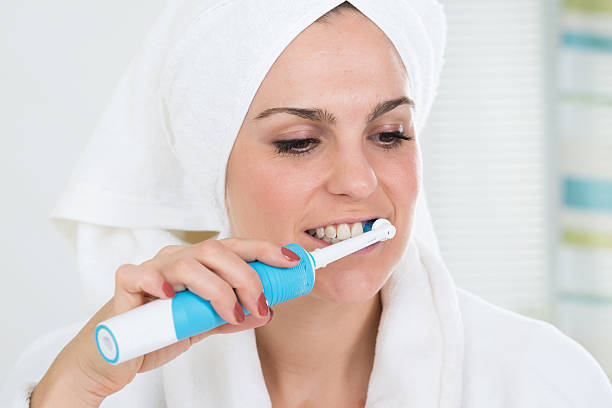 istock Woman Brushing Teeth With Electric Toothbrush 609700246