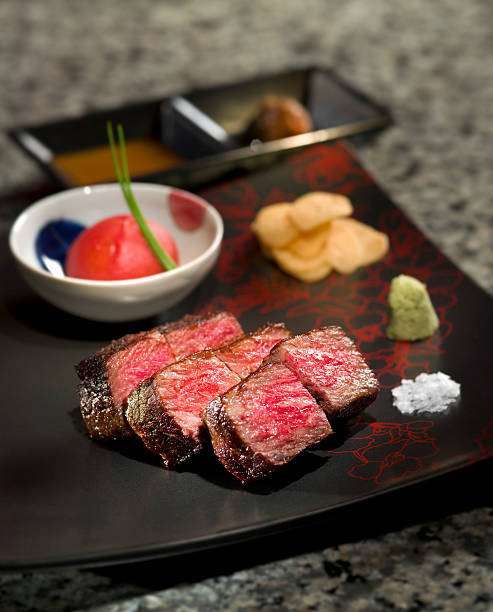 Delicious roasted Teppanyaki Japanese Yaeyama wagyu beef with wa Delicious roasted Teppanyaki Japanese Yaeyama wagyu beef with wasabi and toamtoes sauce on black platter wagyu beef stock pictures, royalty-free photos & images