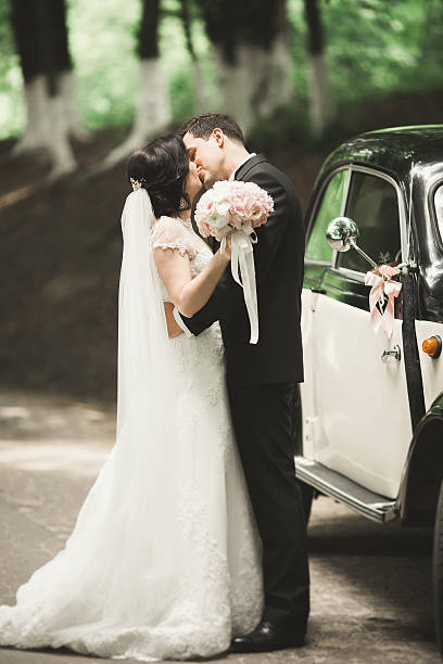 istock Beautiful wedding couple posing near splendid retro car 609709244