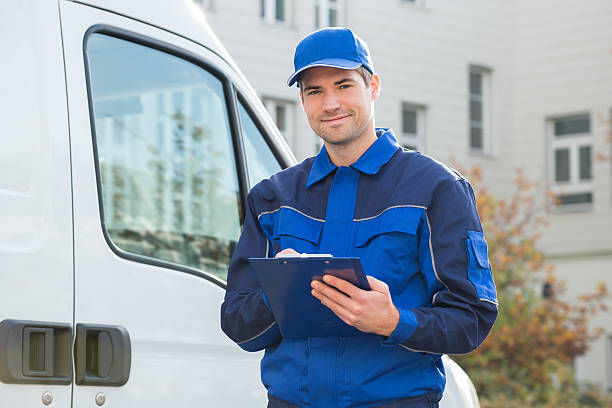 istock Delivery Man In Uniform Holding Clipboard By Truck 609711414