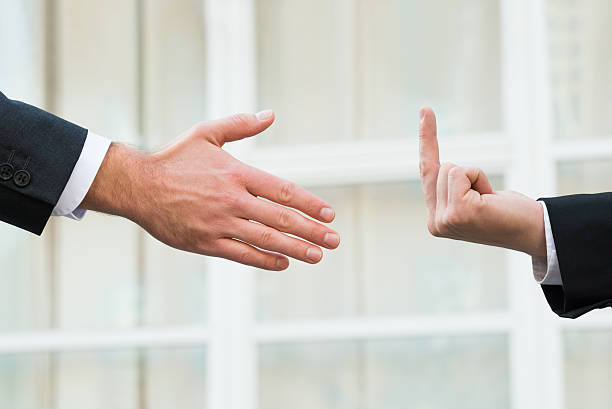 istock Businessman Showing Middle Finger To Partner Offering Handshake 609711994