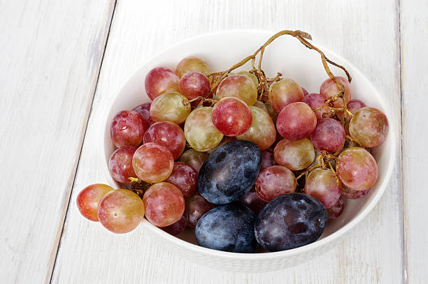 istock Plums and grapes in bowl on the white wooden table 609713714
