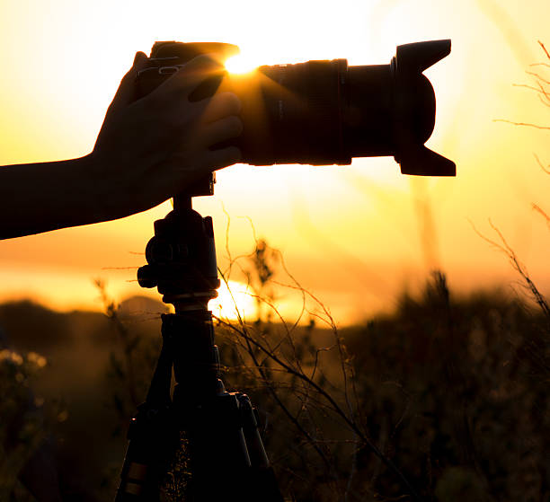 istock Professional photo camera on a tripod silhouette in the sunset 609715978