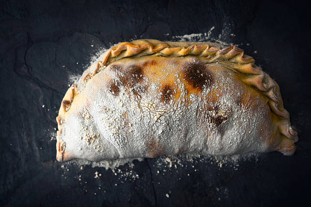 Pizza Calzone with flour on the dark  stone background top view horizontal