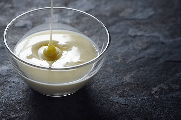 Pouring condensed milk in the glass bowl horizontal stock photo