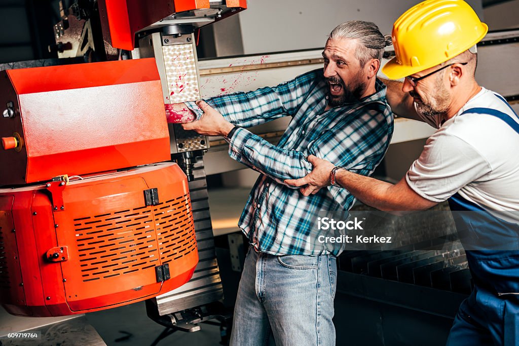 Worker caught in the machine and seriously injured Worker with out safety equipment caught in the machine and seriously injured, other worker is trying to help him Misfortune Stock Photo
