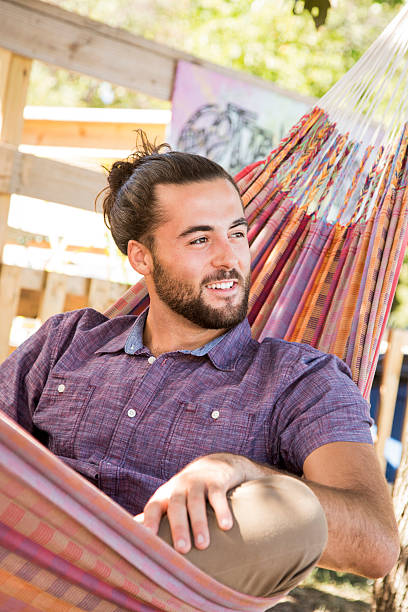 istock Young Man with Hair Bun and Beard sitting in hammock 609719960