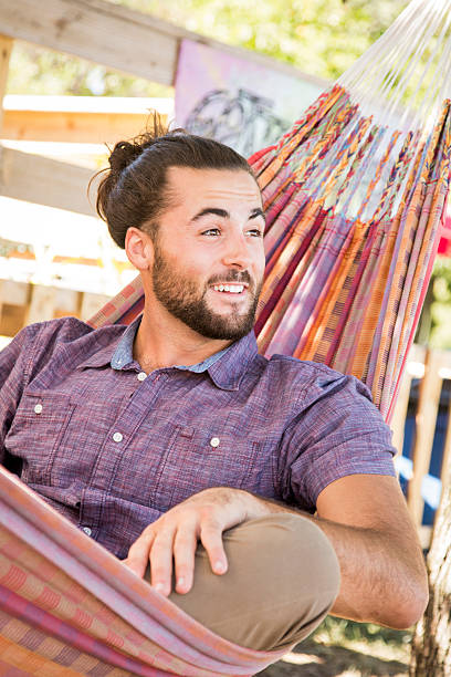 istock Young Man with Hair Bun and Beard sitting in hammock 609720032