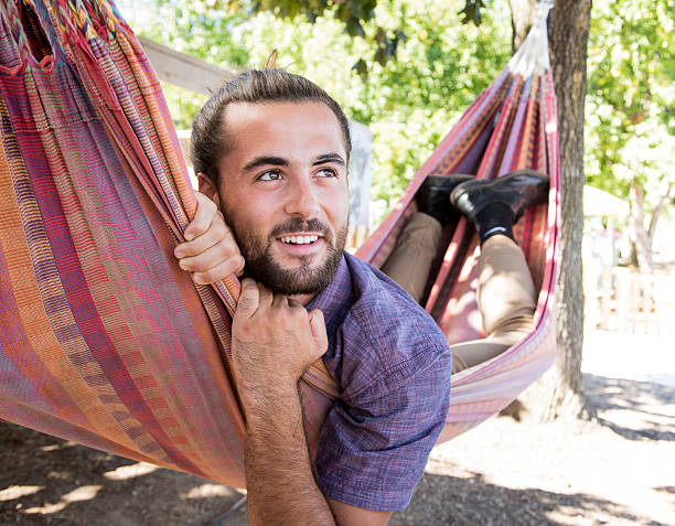 istock Young Man with Hair Bun and Beard sitting in hammock 609720174