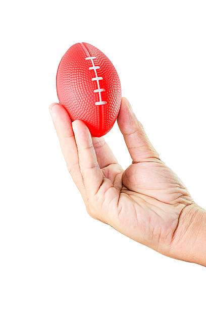 istock hand holding miniaturized rubber rugby ball over white background 609720860