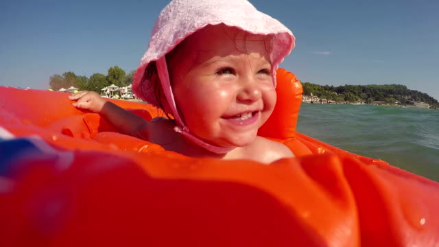 baby girl in swimming tube - swimming , relaxing , sunbathing - first time in sea water
