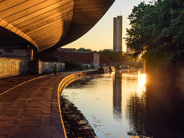 Westway flyover on the Grand Union Canal London, England - July 19, 2016: The Trellick Tower housing block and Westway road flyover are reflected in the waters of the Grand Union Canal at sunset in west London, while joggers and pedestrians enjoy the towpath. trellick tower stock pictures, royalty-free photos & images