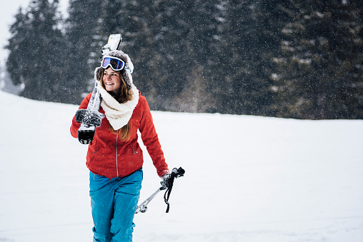 A skier smiles in a safety ski helmet and goggles against the backdrop of the picturesque Alpine mountains. Active sports people and success concept image.