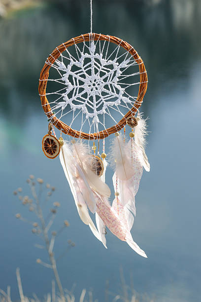 istock Handmade dream catcher with white doily on background of lake 609809328