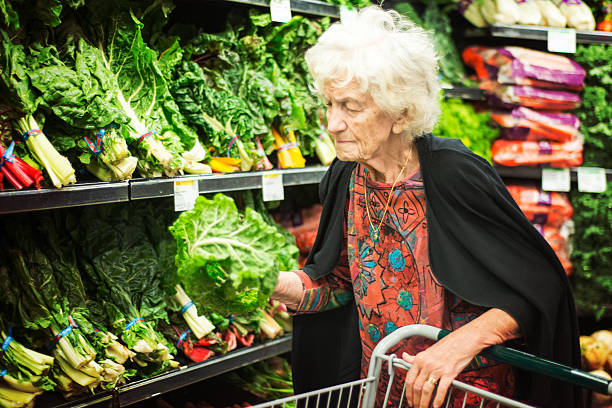 donna anziana che fa shopping per verdure nel negozio di alimentari - senior adult aging process supermarket shopping foto e immagini stock