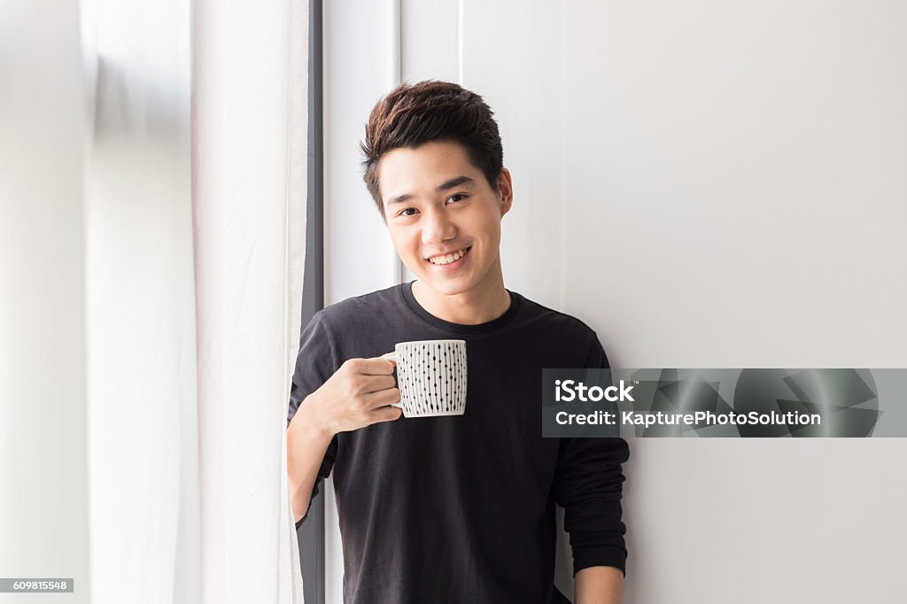 Asian boy Asian boy smiling posing for the camera while holding a coffee mug Men Stock Photo