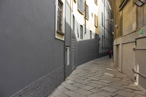 Milan, Italy - April 16, 2015: Via Bagnera narrow street in Milan city center, with a person in the very background