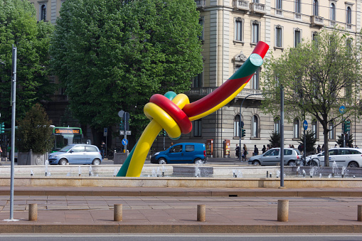 Milan, Italy - April 16, 2015: Knot giant sculpture in Milan Piazza Cadorna, with milanese building and cars in the background