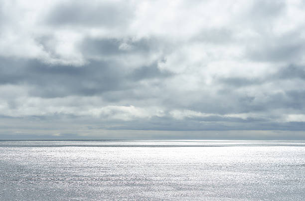 cielo nublado dramático sobre el agua oscura ondulación del mar superficial, luz solar - water wave sea tranquil scene fotografías e imágenes de stock