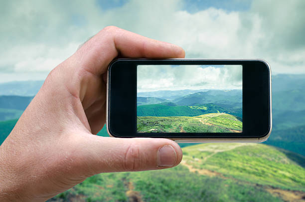 istock phone in a man's hand, mountain landscape photographs on 609820114